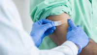 Doctor wearing gloves placing a bandaid on a patient's arm